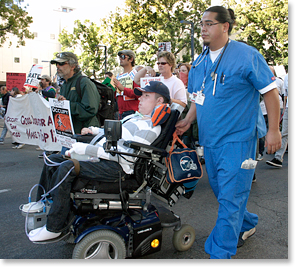 Raul Carranza joins in leading the Human Rights March for Labor/Occupy SD through downtown San Diego. He is accompanied by his nurse Sam Uybungco. Photos by Nic Paget-Clarke.