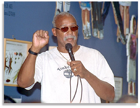 John Carlos, the bronze-medal winning athlete famous at the 1968 Mexico City Olympics for raising his black-gloved fist in silent protest while on the victory stand, along with gold-winning Tommy Smith. In this photo taken in South Central Los Angeles he speaks to community members of that moment and his life of helping young people and fighting racism. After his talk, he signed copies of a newly published biography by C.D. Jackson Jr. - July 2001. Photo by Nic Paget-Clarke.