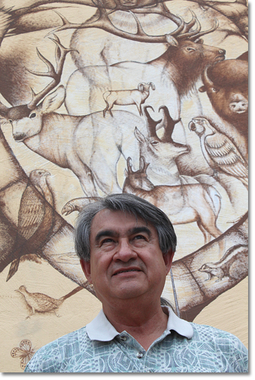 Dr. Gregory Cajete at the All Indian Pueblo Cultural Center in Albuquerque, New Mexico in front of a section of a mural by D.C. Arquero ©'98. Photo by Nic Paget-Clarke.