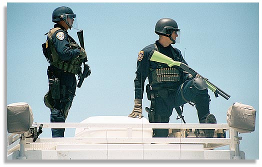 San Diego police, on top of a police vehicle, look over the approximately 1,000 people marching through the streets of downtown San Diego to protest the genetic engineering of food crops and other organisms on the opening day of the international biotech convention in San Diego, California. June 24, 2001. The budget for the San Diego police, sheriffs and California Highway Patrol for the convention was approx. $4,000,000. Photo by Nic Paget-Clarke.